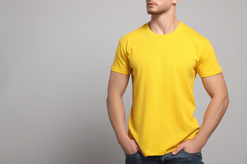 Man wearing yellow t-shirt on light grey background, closeup. Mockup for design