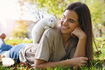 Wall Mural - Happy woman with cute white rabbit on grass in park