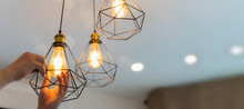 Handyman Choosing Between Energy Save And Cheap Incandescent Lamp While Changing Light In The Appartment