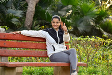 woman sitting on a bench in park showing thumbs up