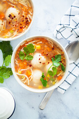 Wall Mural - Potato balls soup with noodles and vegetables in white bowl, white background. Vegan food concept.