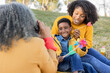 © Westend61 - Woman talking photos of daughter and grandson sitting in park