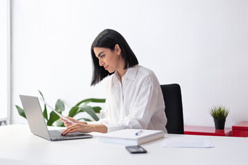 Businesswoman with document typing on laptop at desk