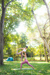 © chokniti - Fitness lifestyle and body healthy concept, Portrait of young Asian woman doing Yoga in the garden for a workout, Practicing exercise in the park outdoor with happy relaxation in vacation time