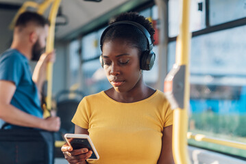 Poster - African american woman riding in a bus and using a smartphone