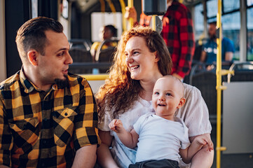 Happy parents and son riding in bus while baby sits in mother lap.