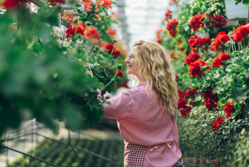 Wall Mural - Young woman working in a greenhouse and taking care of the plants