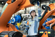 © Nassorn - Industrial engineer working on robot maintenance in AI futuristic electronic technology factory. Female technician checking automated robotic machine. Modern smart woman empowerment in industry 4.0.