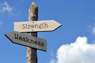 Wall Mural - Strength and weakness - wooden signpost with two arrows, sky with clouds