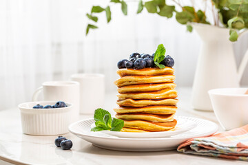 Poster - Morning table, homemade  breakfast, stack of pancakes with blueberries and honey or maple syrup. White window on background.