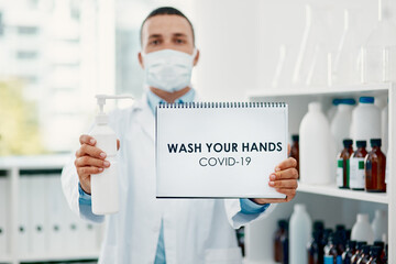 Canvas Print - Keep your hands clean. a scientist holding a sign with wash your hands on it and hand sanitiser in a laboratory.