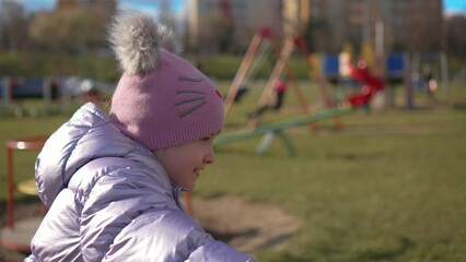 Young girl smiles brightly as she pedals her bike, spinning wheel carrying her to new adventures in slow motion In city park. Happy childhood, sports outdoors in playground
