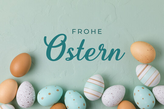 Fototapete - Happy Easter Greeting Card -  German text.  Easter frame of pastel colored eggs on light green background. Flay lay, top view with copy space.
