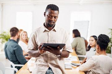 Poster - Driving innovation into all that he does. a young businessman using a digital tablet in an office with his colleagues in the background.