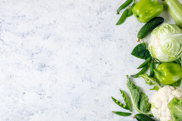 Wall Mural - Border of organic green raw vegetables on white table. Top view of healthy organic food. Copy space