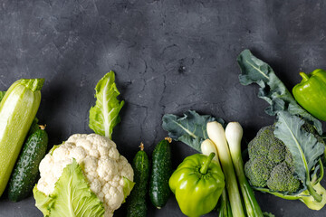 Wall Mural - Border of green raw vegetables on black background. Top view of healthy organic food. Copy space