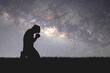 © STOCK PHOTO 4 U - Man silhouette kneeling praying to god hopefully with the beautiful Milky Way