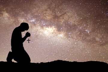 man silhouette kneeling praying to god hopefully with the beautiful milky way