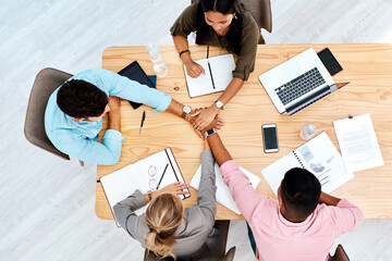 Poster - Motivated to make big profits together. High angle shot of a group of businesspeople joining their hands together in a huddle while working in an office.