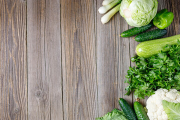 Wall Mural - Border of green raw vegetables on wooden background. Top view of healthy organic food. Copy space