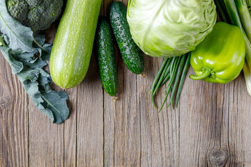 Wall Mural - Border of green raw vegetables on wooden background. Top view of healthy organic food. Copy space