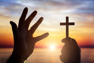 Sticker - Holding up religious cross crucifix to sky across the sea at sunset background