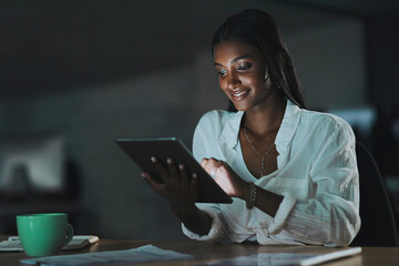 Its time you get connected too. a young businesswoman using a digital tablet in an office at night.