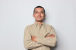 © Terang Bulan Gallery - Portrait of confident smiling Asian young man wearing cream shirt standing with arms folded isolated on white background.