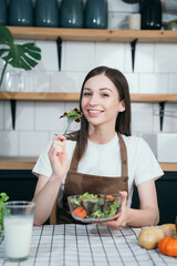 woman using laptop computer searching and learning for cooking healthy food from fresh vegetables and fruits in kitchen room.