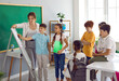 © Studio Romantic - Classmates work together on school project. Elementary school students use whiteboard together with the teacher during lesson. Children take turns writing on whiteboard. Learning and school concept.