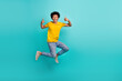 Full body portrait of overjoyed carefree man jumping demonstrate thumb up isolated on cyan color background