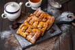 Homemade sweet puff pastries. Baked Puff pastry turnovers with chocolate and fruit filling served on a wooden board with cup and teapot on background. Selective focus, horizontal.