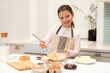 © Prostock-studio - Smiling european little girl in apron makes dough for cookies with whisk, milk flour and eggs on table