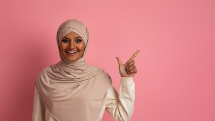 Wall Mural - Nice Offer. Smiling Islamic Woman In Hijab Pointing Aside At Copy Space