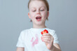 A child's hand is holding a slice of strawberry. A dirty pink stain on the front of a white t-shirt. daily life stain concept