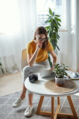 Wall Mural - Young woman designer or freelancer working at home using computer sitting at table at home