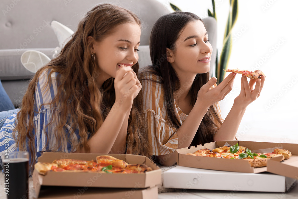 Young women eating tasty pizza at home