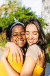 © Xavier Lorenzo - Vertical portrait of candid happy multiracial best women friends embracing outdoors. Close up view of two diverse girls hugging each other with closed eyes smiling. Female friendship concept
