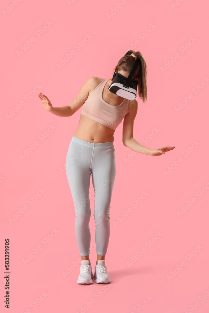 Pretty young woman in VR glasses on pink background