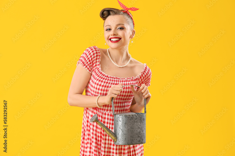 Young pin-up woman with watering can on yellow background