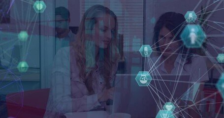 Poster - Animation of globes of icons over two diverse businesswomen discussing over a laptop at office