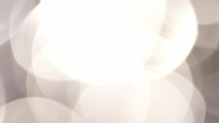 Wall Mural - Smooth circular motion of large silver bokeh abstract background. Slowly moving and shimmering unfocused circles. Abstraction moving background with tints of light on large bokeh lights.