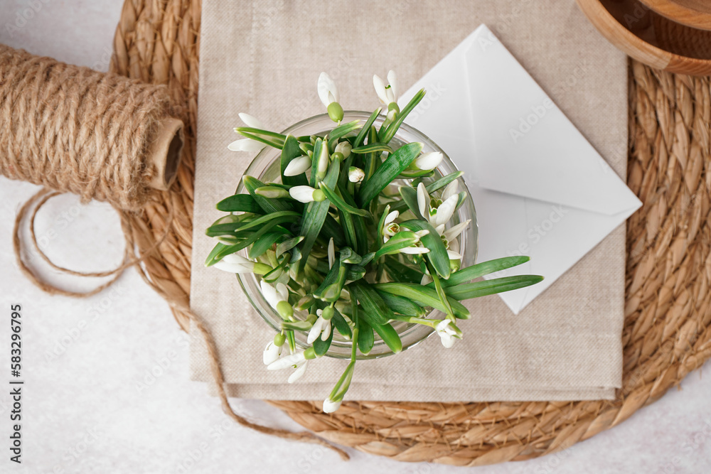 Glass with beautiful snowdrops on grey table