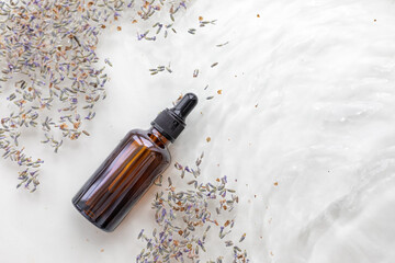 Wall Mural - Amber bottle of lavender essential oil. Flat lay concept. Light background with water waves.