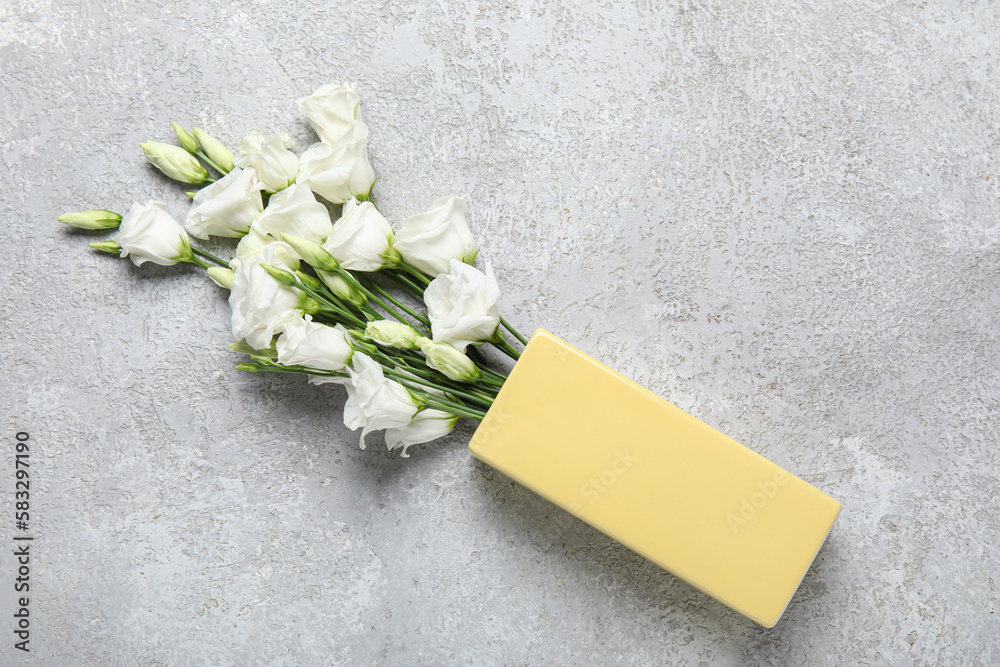 Overturned vase with beautiful eustoma flowers on grunge background