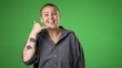 Portrait of smiling happy gender fluid non binary young woman 20s smiling and giving CALL ME gesture with hands isolated on green screen background.