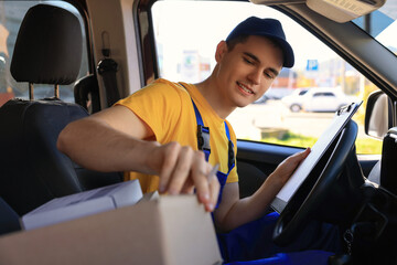 Wall Mural - Courier with clipboard checking packages in car