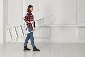 Poster - Young beautiful woman with metal stepladder indoors. Room renovation