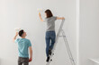 © New Africa - Young man and woman painting wall with rollers indoors. Room renovation