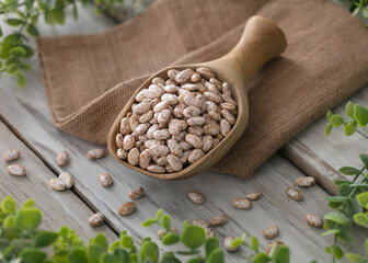 Full spoon with beans of bean (pinto beans). White wood rustic table background.